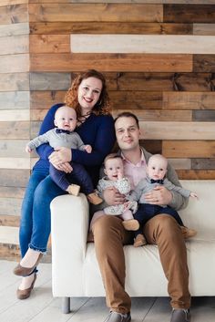 a man and woman sitting on a couch with two babys