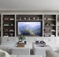 a living room filled with white furniture and a flat screen tv mounted on the wall