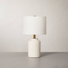 a white ceramic table lamp with a gold metal base