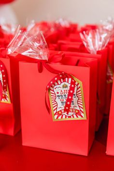 small red bags with tags on them are sitting on a table in front of some balloons