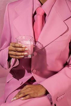 a woman in a pink suit holding a drink