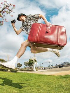 a man jumping in the air with a red suitcase