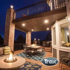 a deck with fire pit and seating area at night