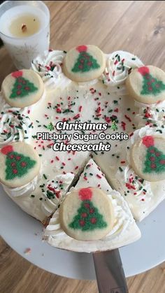 a christmas cake with white frosting and green sprinkles is on a plate next to a candle