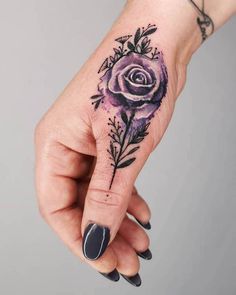 a woman's hand with a purple rose tattoo on it