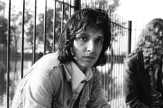 black and white photograph of two people sitting next to each other in front of a fence