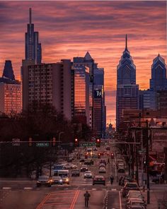 a city street filled with lots of traffic under a colorful sky covered in clouds at sunset