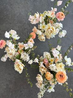 three bouquets of flowers sitting on top of a gray surface with white and pink flowers