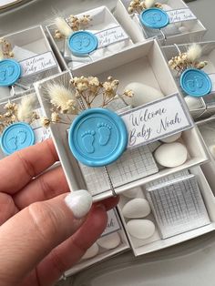 a person holding a small box with baby's footprints on it and some flowers