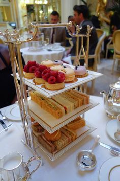 three tiered trays filled with pastries on top of a white table cloth