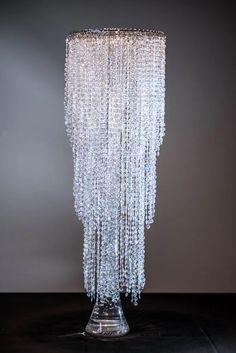 a tall glass vase with beads hanging from it's sides on a black table