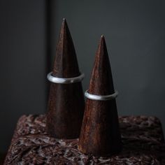 two small wooden cones sitting on top of a brown cloth covered table next to each other