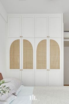 a bedroom with white cupboards and an unmade bed in front of the closet