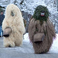 two people in furry costumes walking down a street with snow on the ground behind them