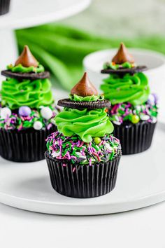 three cupcakes with green frosting and sprinkles on a plate