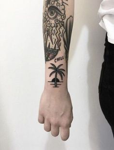 a person's arm with a tattoo on it and a palm tree in the foreground