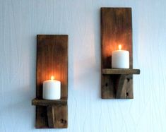 two wooden wall sconces with lit candles on them against a white painted wall