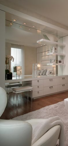 there is a large mirror in the middle of this room with white cabinets and drawers