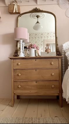 a dresser with a mirror and lamp on top of it