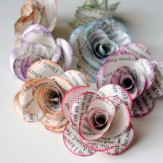 several rolled up flowers sitting on top of an open sheet of paper with words written in it