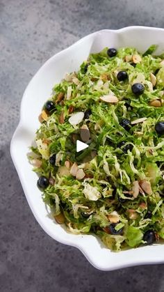 a white bowl filled with lettuce and olives on top of a table