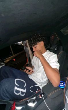 a young man sitting in the back seat of a car while using his cell phone