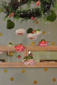 pink flowers are hanging from the ceiling in front of polka dot wallpaper and mirrors