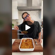 a woman is holding a spoon over a casserole dish