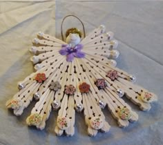 a decorative wooden decoration with buttons and flowers on it's wings, sitting on a white sheet