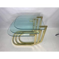 three glass tables with gold metal bases