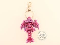 a pink dragon keychain with flowers on it