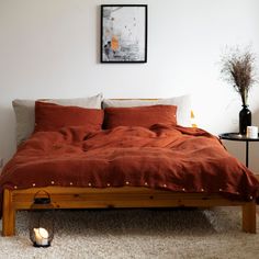 a bed with an orange comforter in a bedroom next to a table and lamp