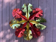 a paper flower is hanging on the side of a wooden wall with purple boards behind it