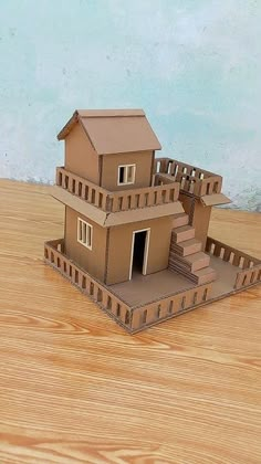 a paper model of a house sitting on top of a wooden table