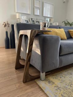 a grey couch sitting on top of a hard wood floor next to a wooden table