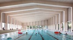 an indoor swimming pool with several people in it and two red floats floating on the water