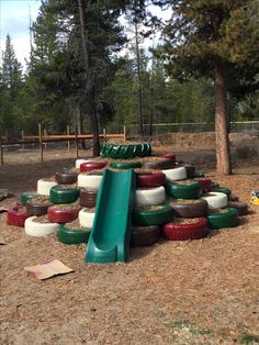 there are many tires stacked on top of each other in the park with a slide