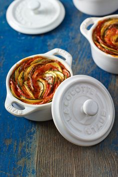 three white casserole dishes filled with food on top of a blue wooden table