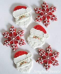 four decorated christmas cookies with santa clause and snowflakes on white tablecloth background