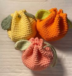 three crocheted purses sitting on top of a white table next to each other