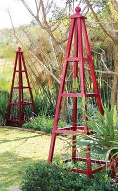 two tall red metal plant stands in a garden