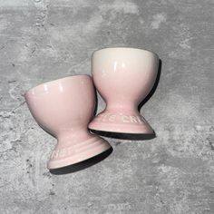 two pink vases sitting next to each other on a cement surface with the word love spelled in white letters