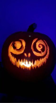 a carved pumpkin with swirly eyes on it's face in the night sky