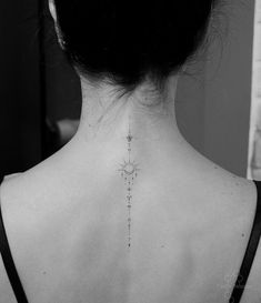 the back of a woman's neck with a cross tattoo