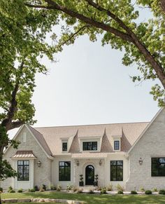 a large white house with lots of windows and grass in front of the door is surrounded by trees