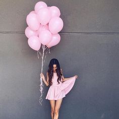 a woman in a pink dress holding balloons