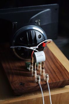 an electronic device is plugged in to the wooden board with three wires running through it