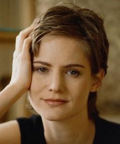 a close up of a person wearing a black shirt and holding their hand on her head