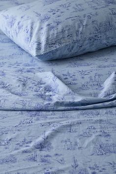 an unmade bed with blue sheets and pillows on top of it, next to a pillow case