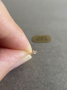 a person's hand holding a tiny diamond ring